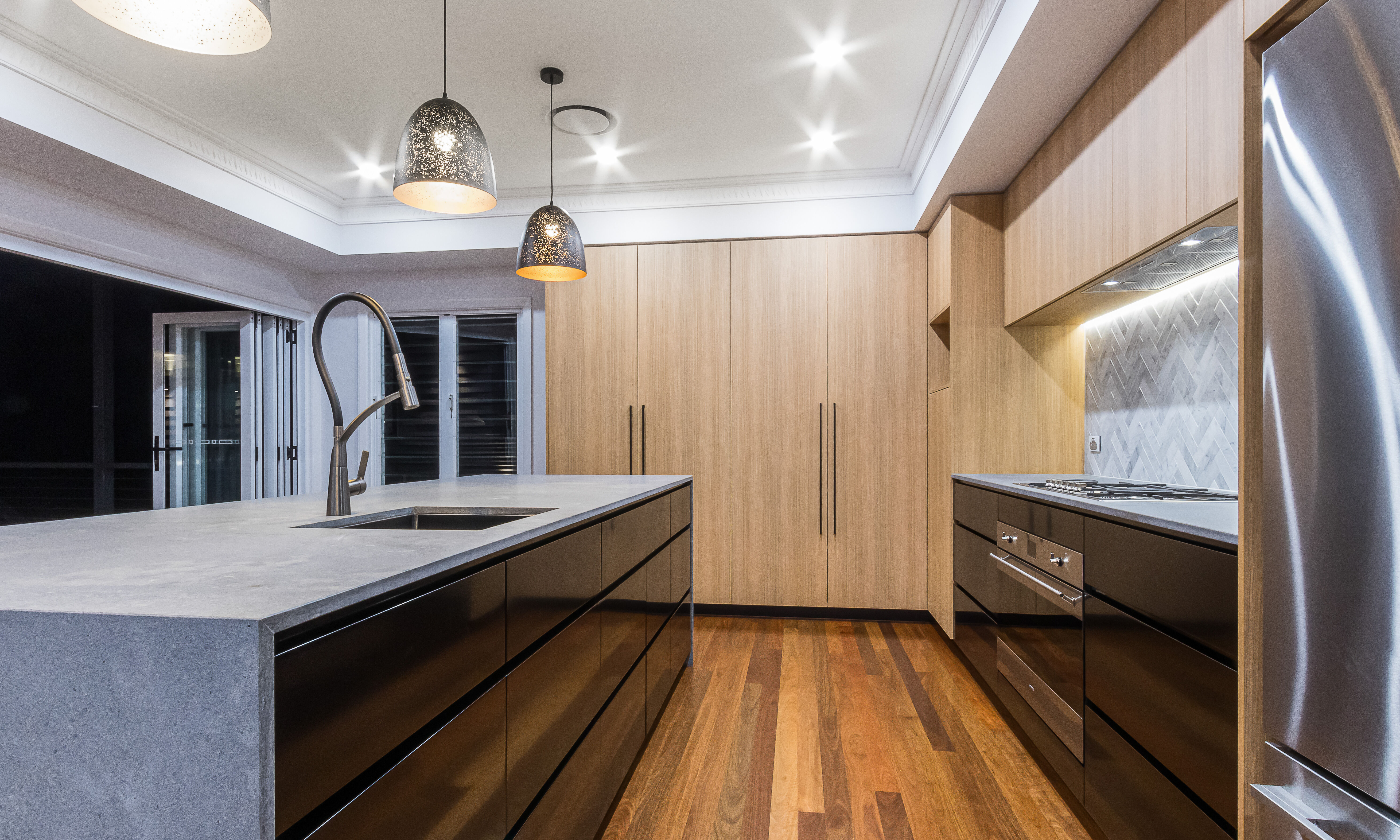 ornate cornice-timber veneer kitchen-black cabinetry-pendant lights