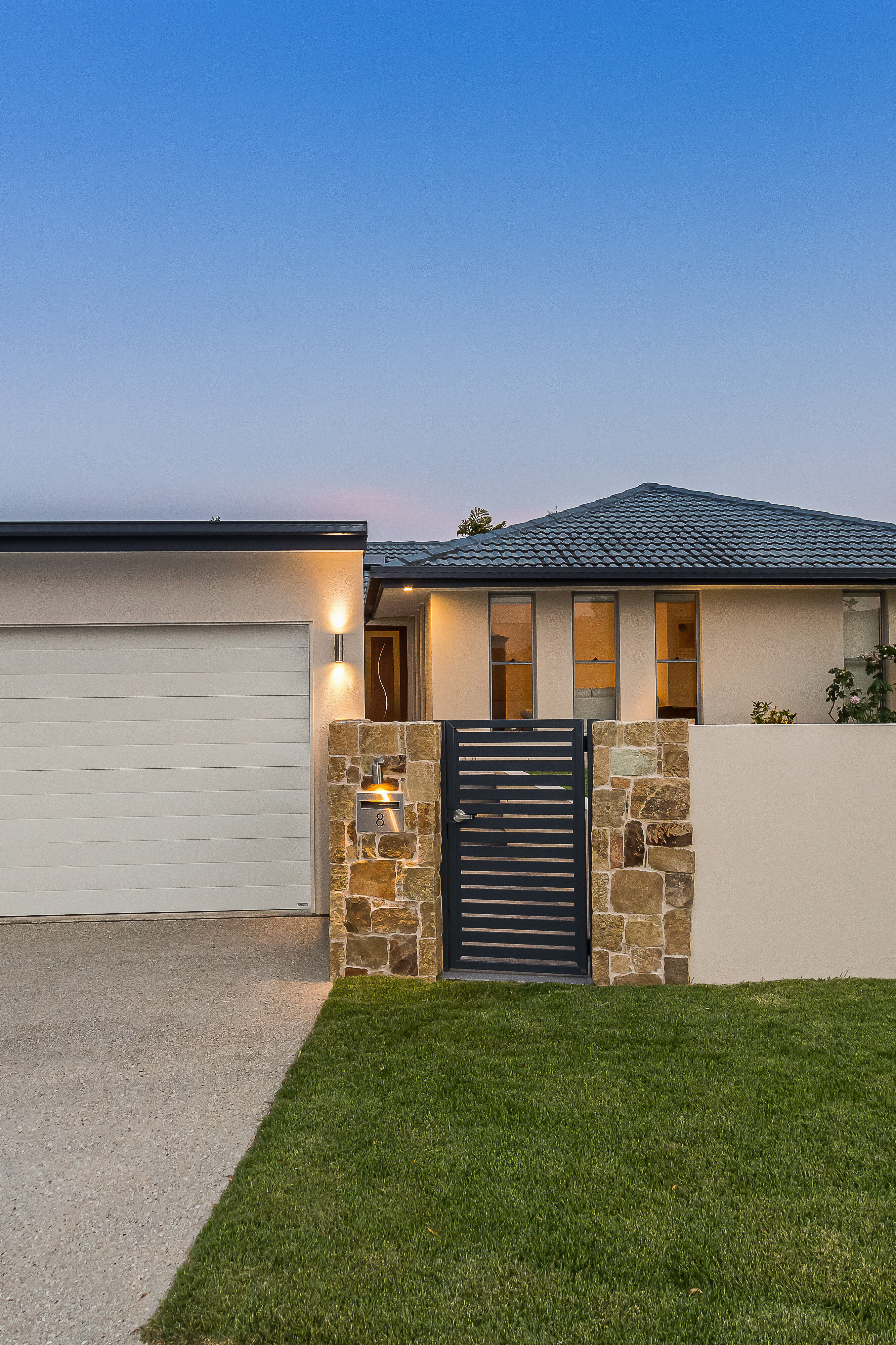 Double carport with rendered front wall and exposed concrete driveway