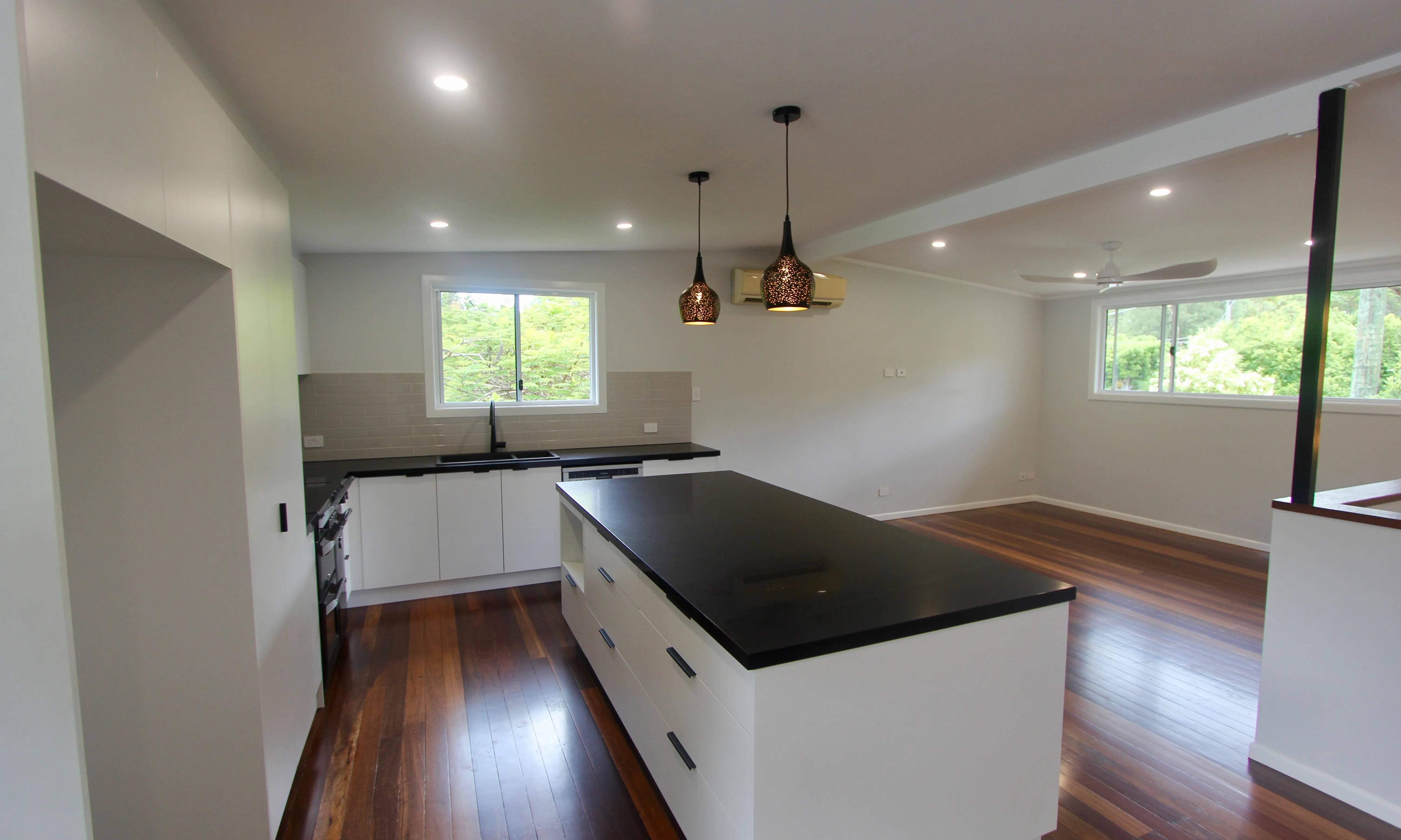 Kitchen island with black stone top and black pendant lights