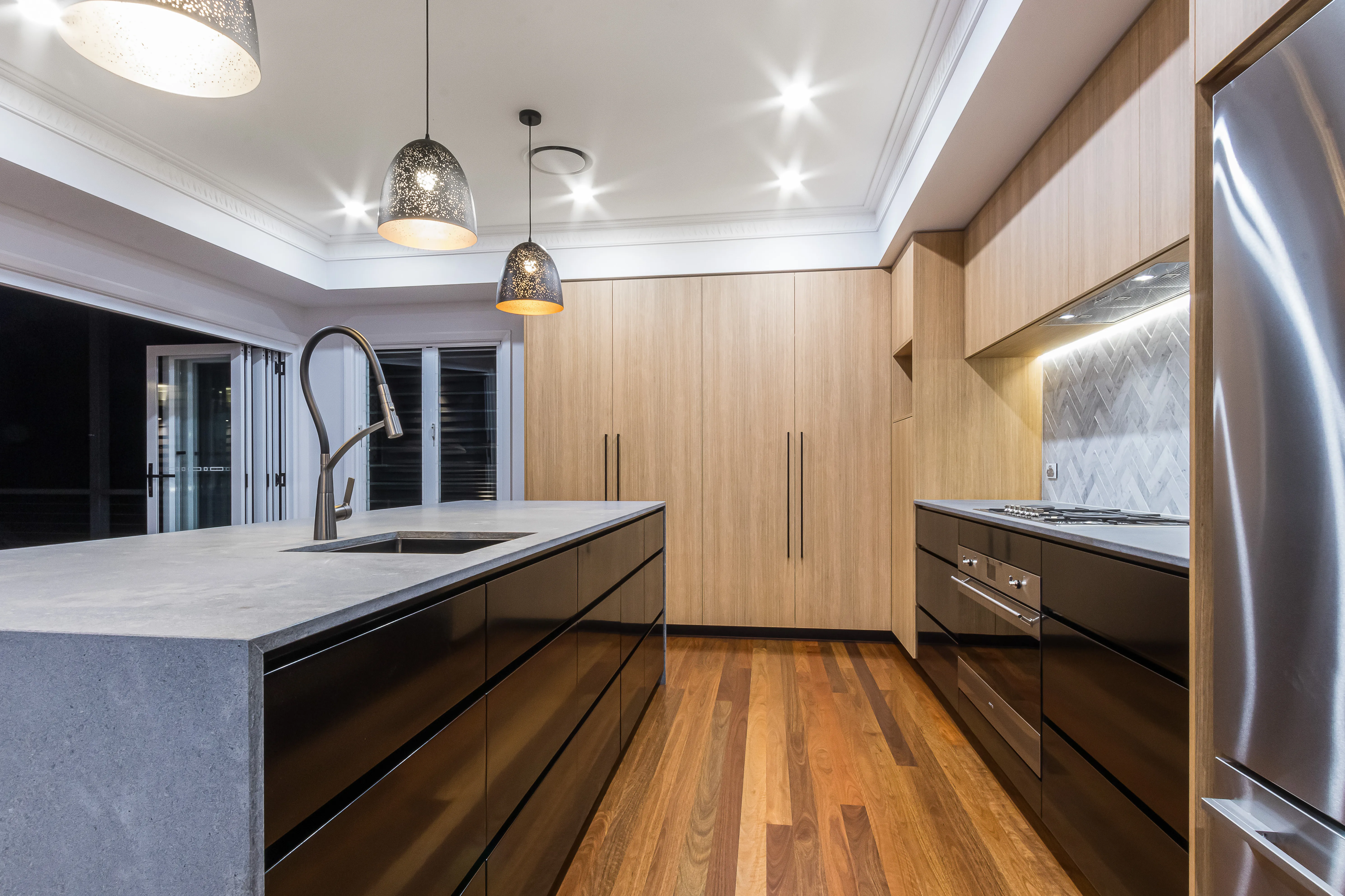 ornate cornice-timber veneer kitchen-black cabinetry-pendant lights