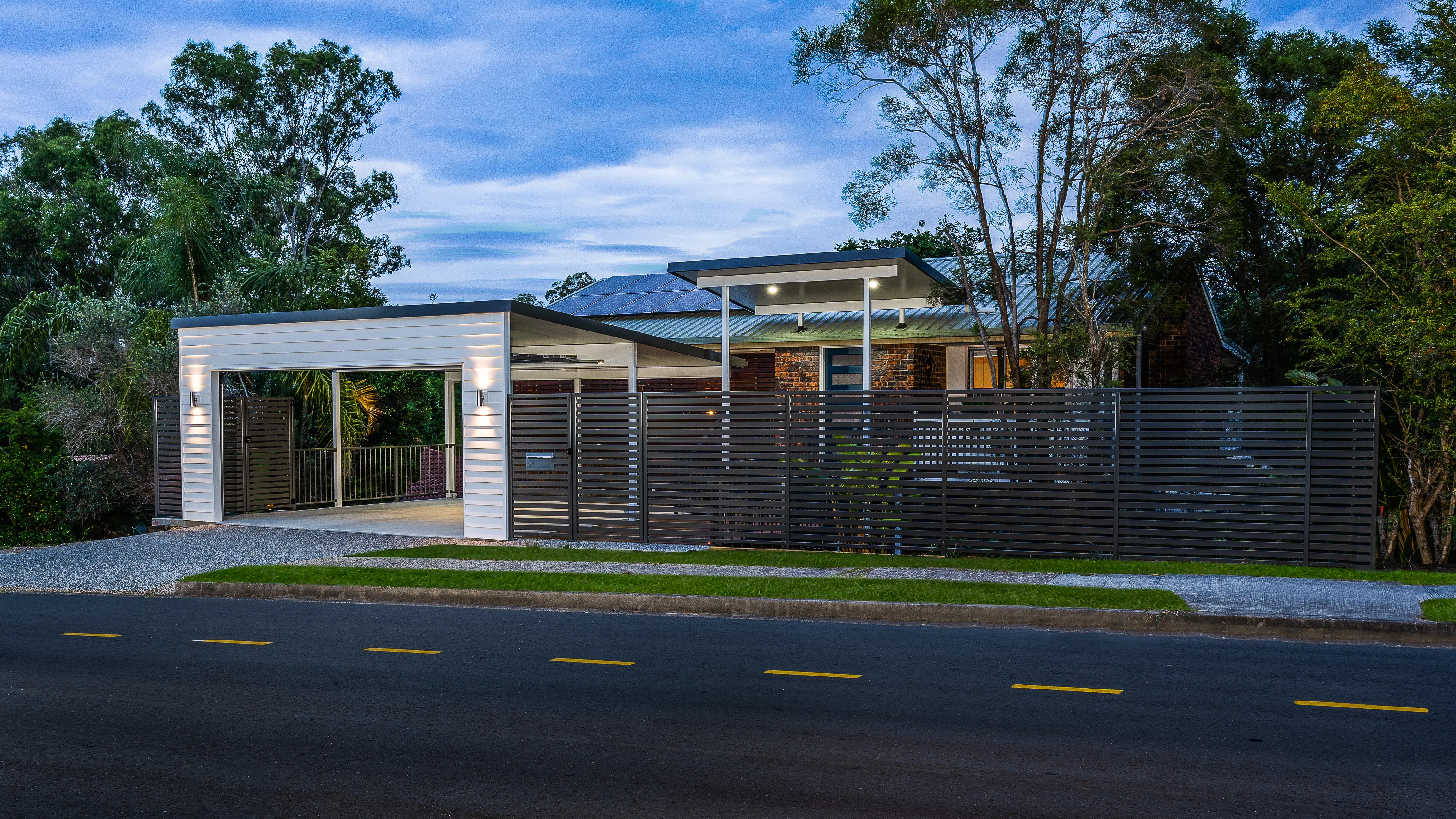 Carport and boundary fence and exposed concrete driveway