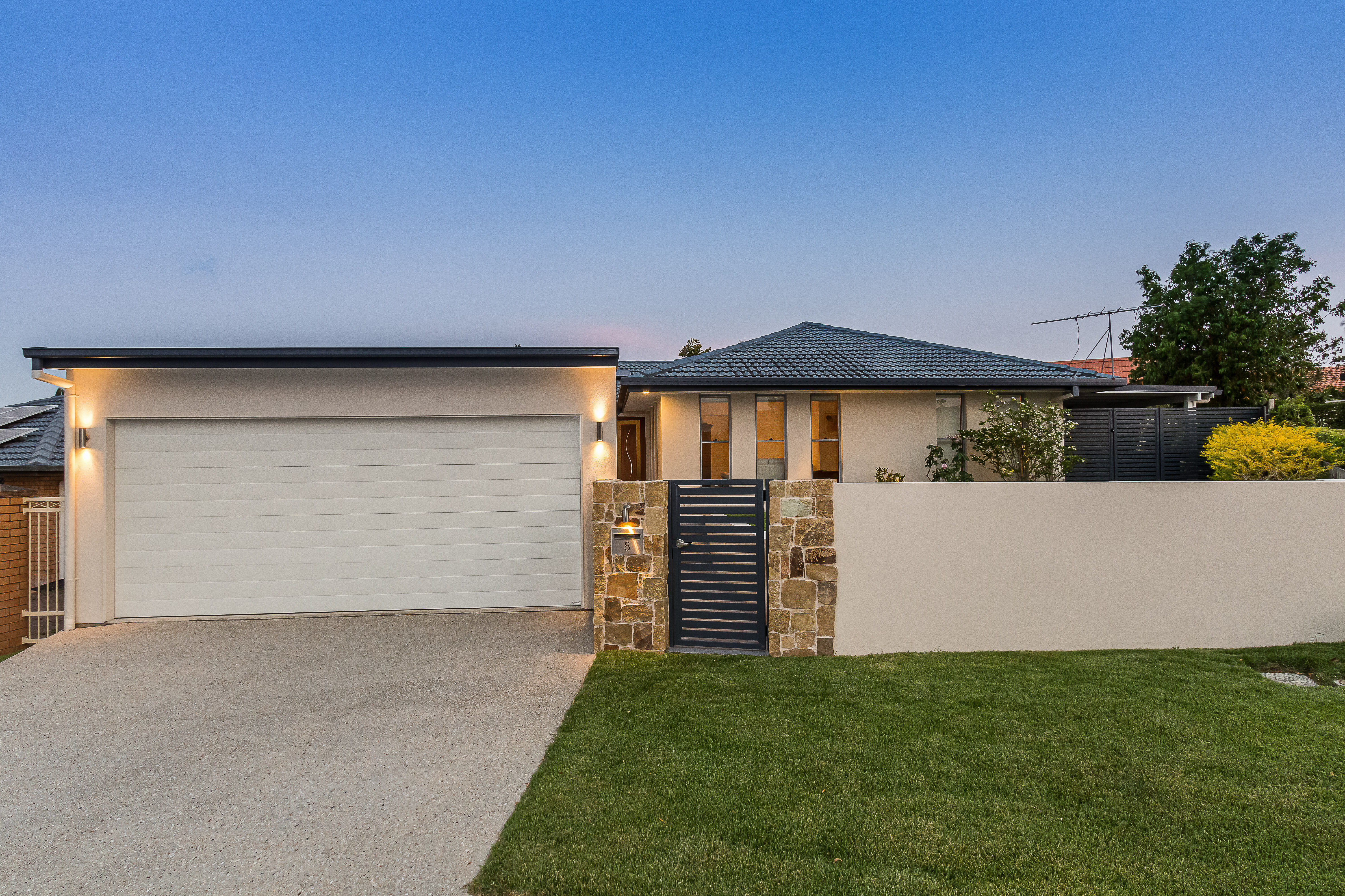 Double carport with rendered front wall and exposed concrete driveway