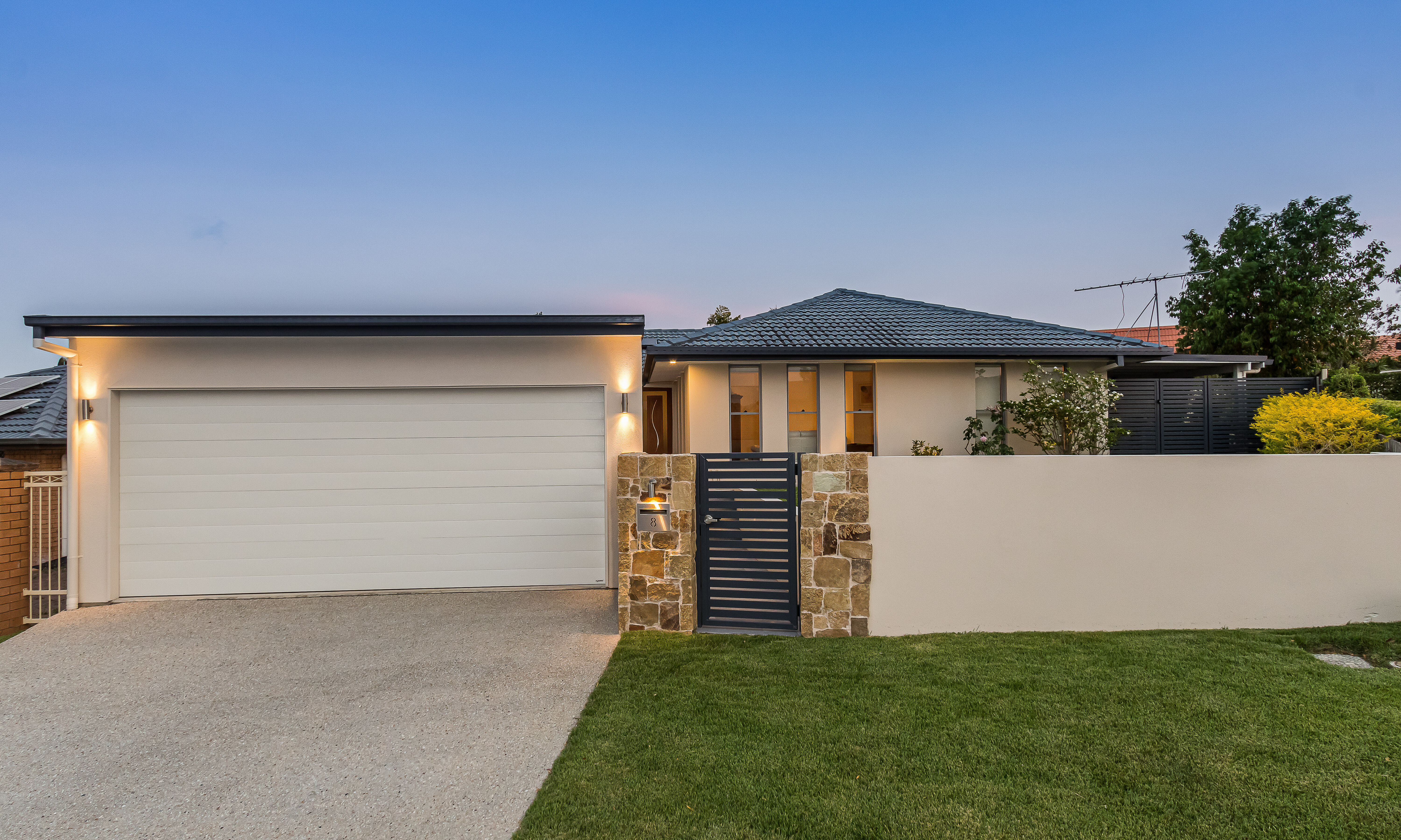 Double carport with rendered front wall and exposed concrete driveway