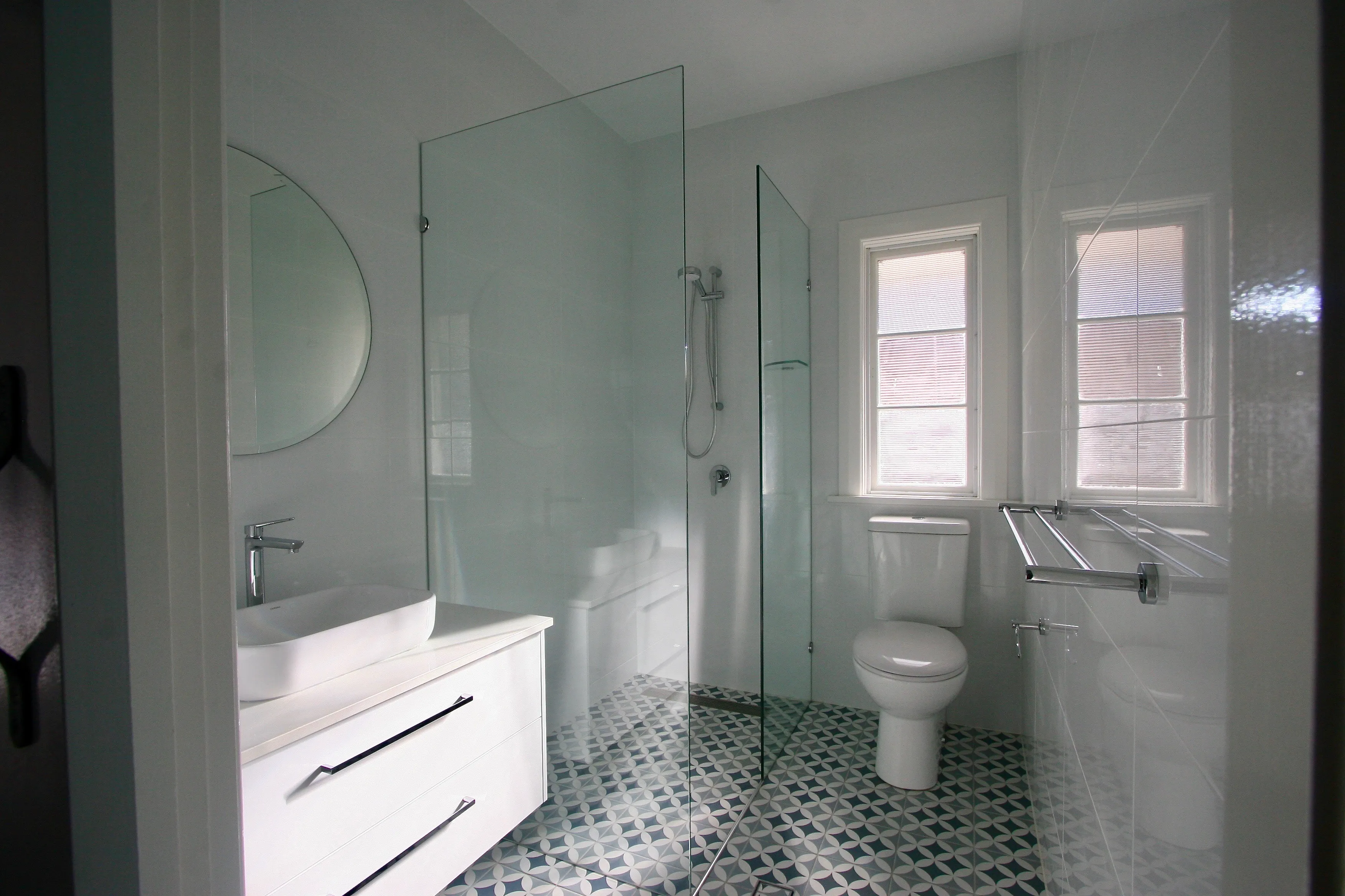Frameless shower screen and blue and white tiles in bathroom