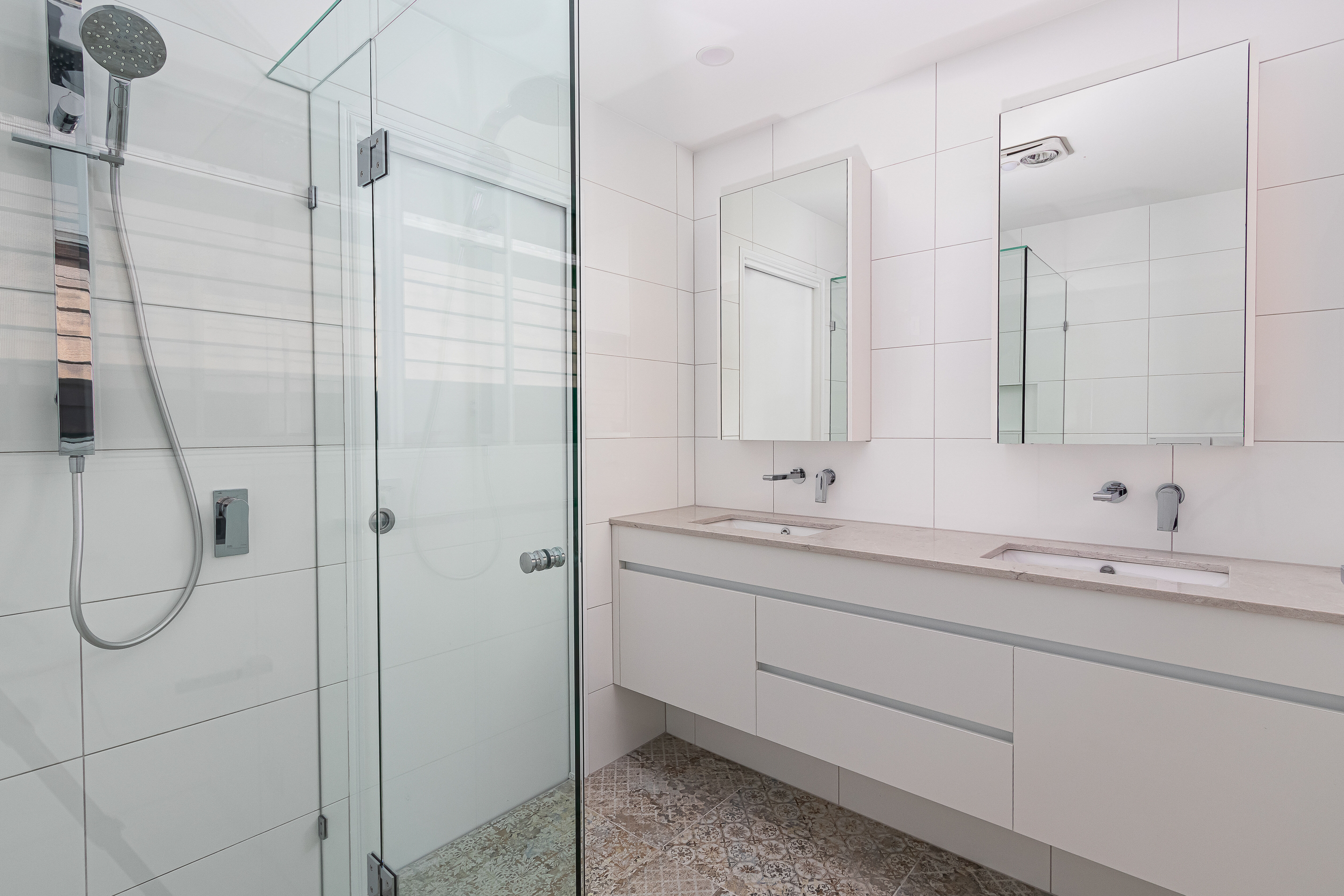 Ensuite with floating vanity, mirrored shaving cabinets and fixed glass shower screen