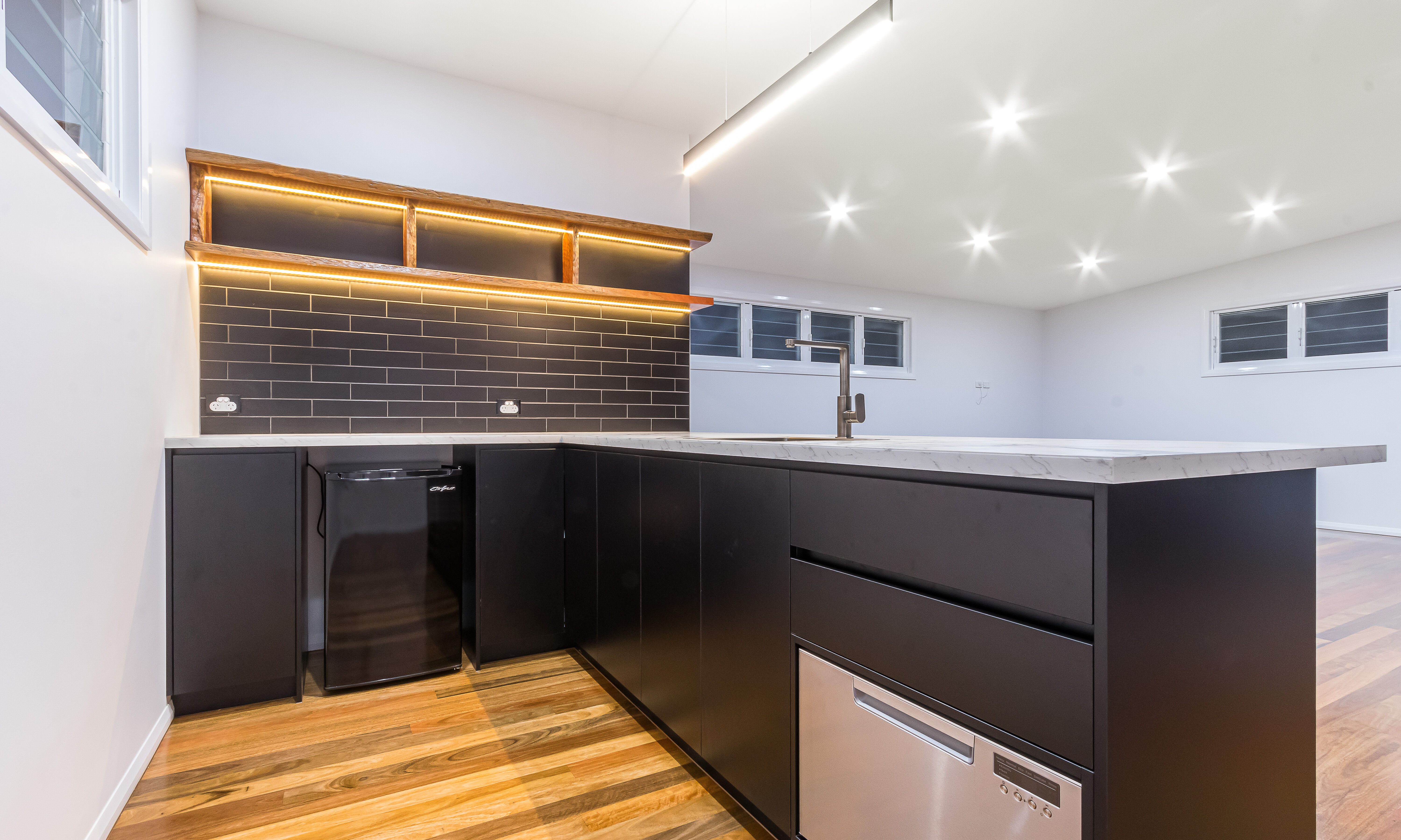 black kitchen-black subway tiles-timber floating shelves