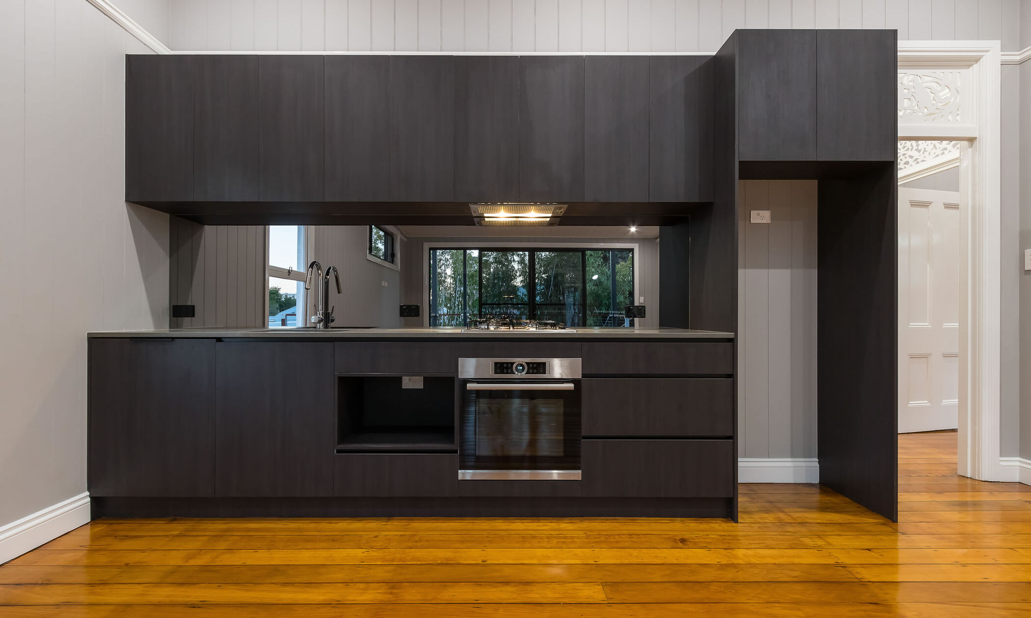 Black kitchen with glass mirrored splashback