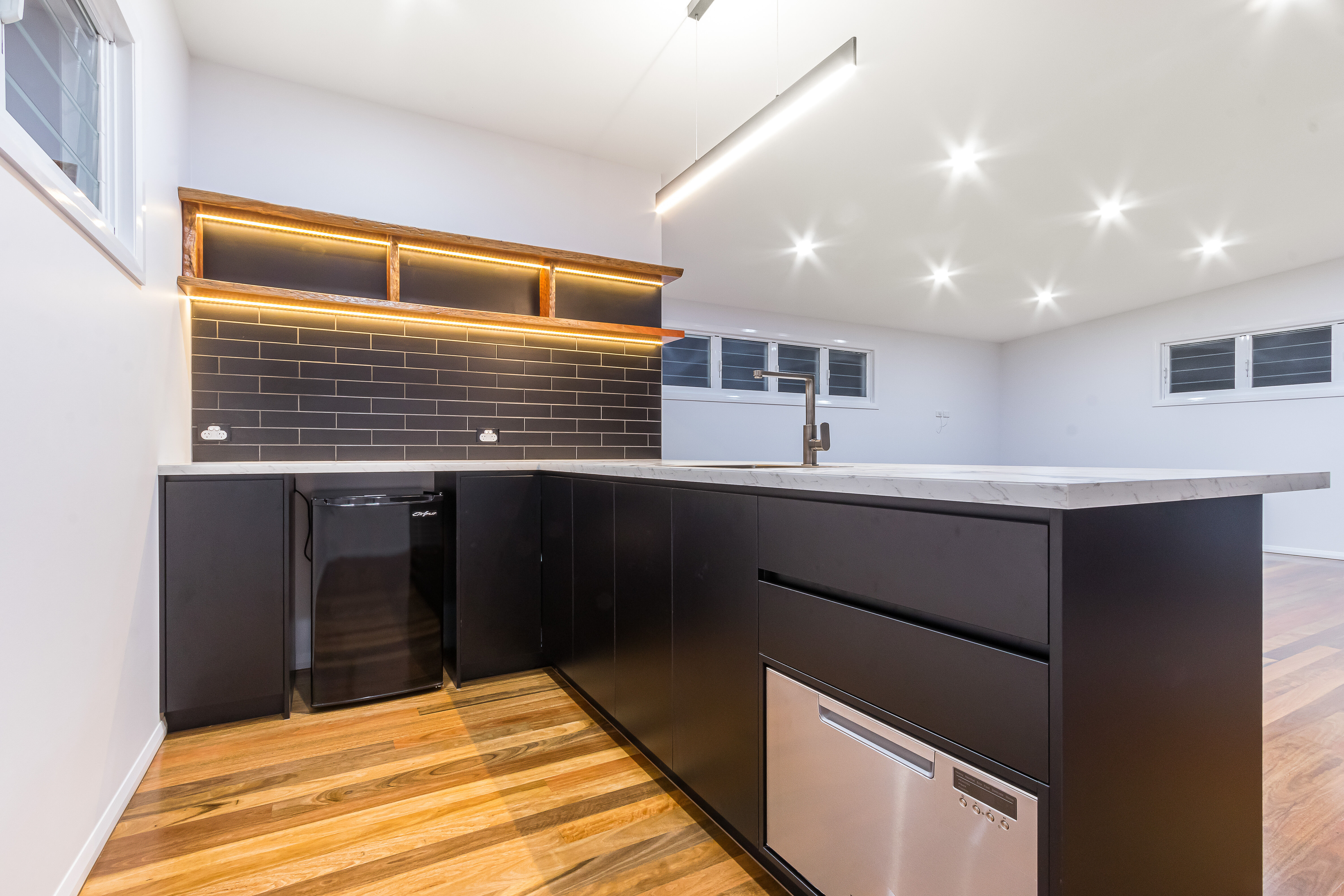 black kitchen-black subway tiles-timber floating shelves