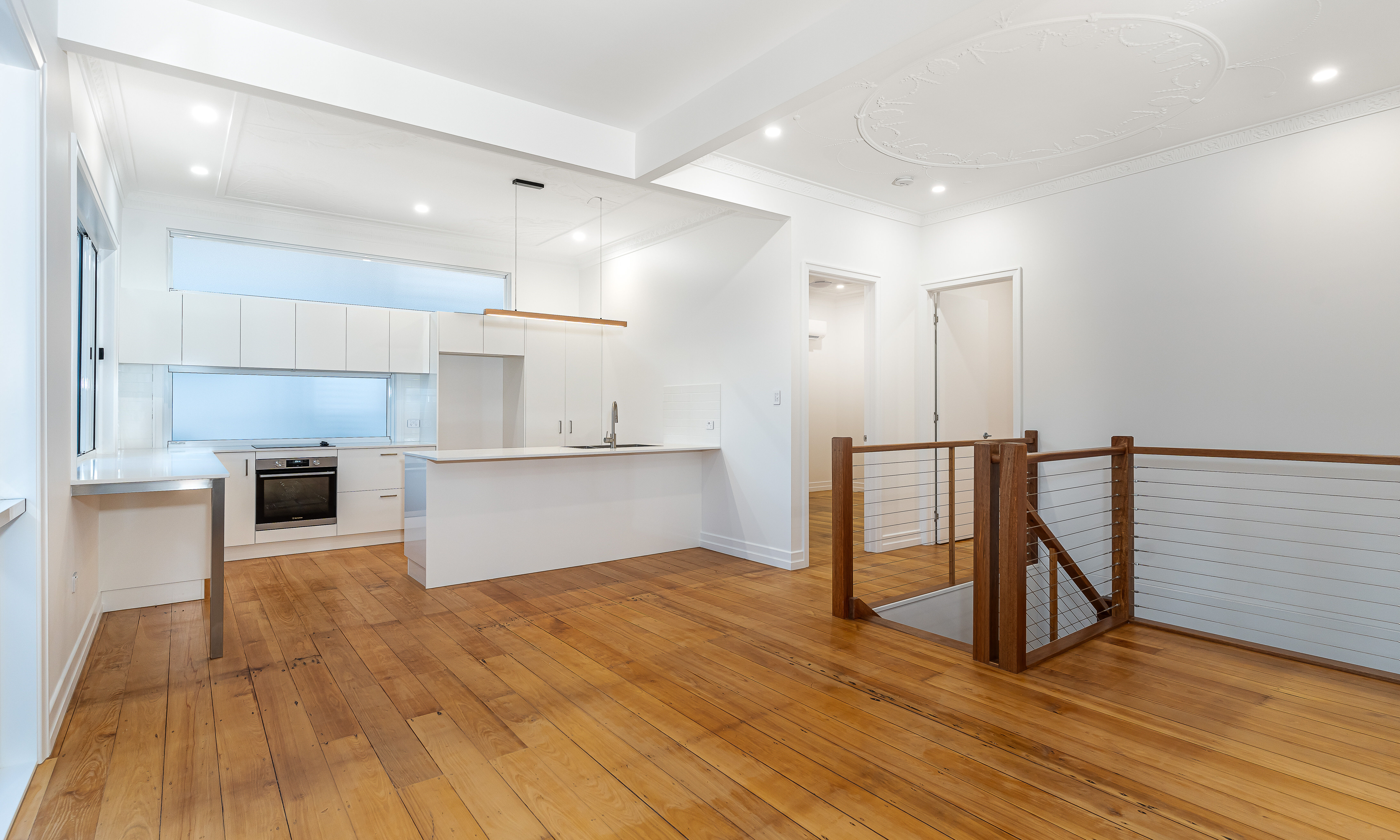 white kitchen- stone bench top-timber stairs-wire balustrade