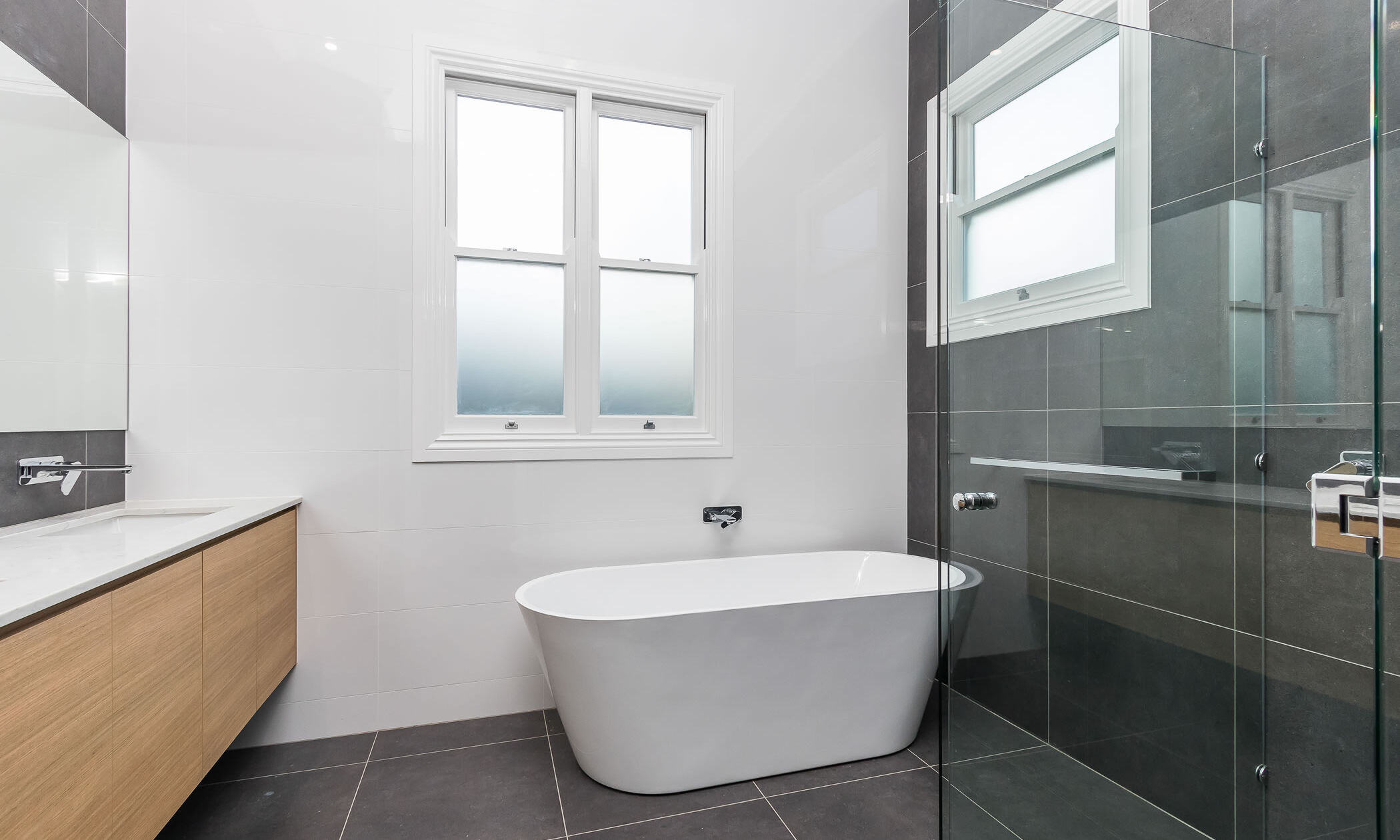 Bathroom with freestanding bath and frameless shower screen