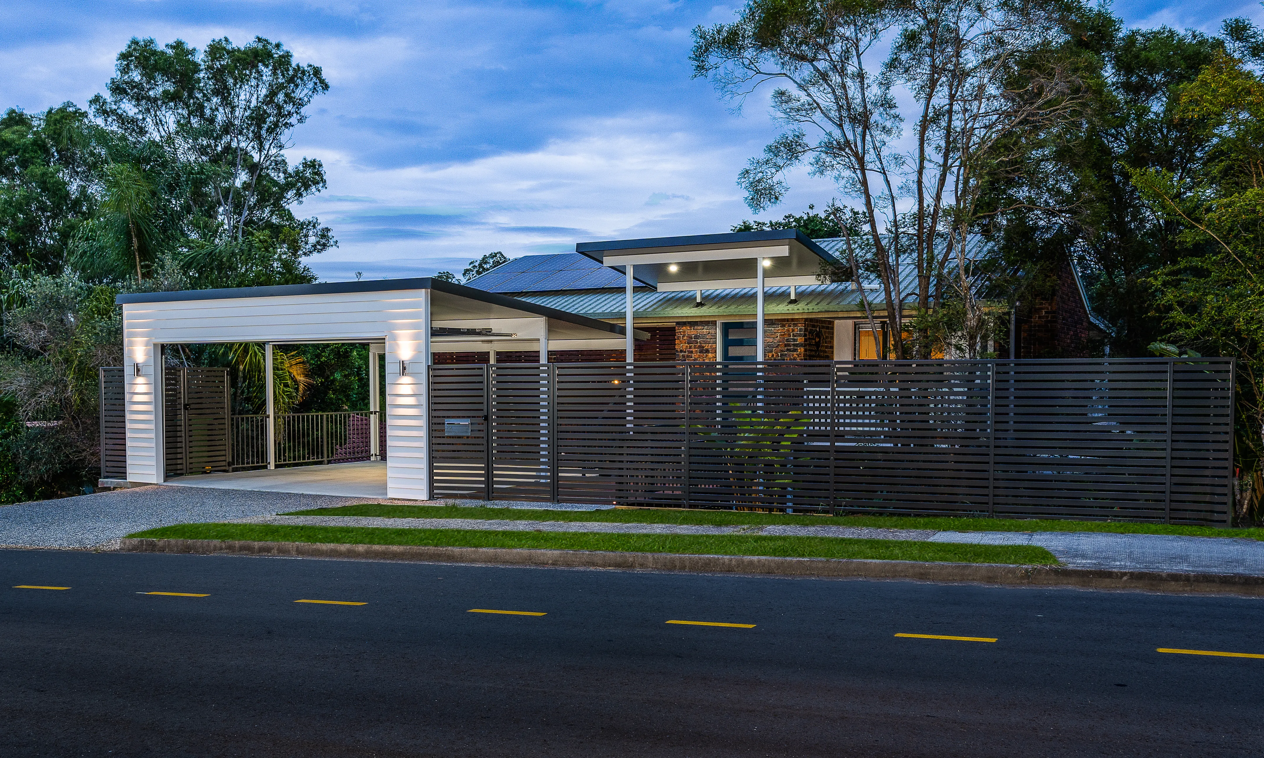 Carport and boundary fence and exposed concrete driveway