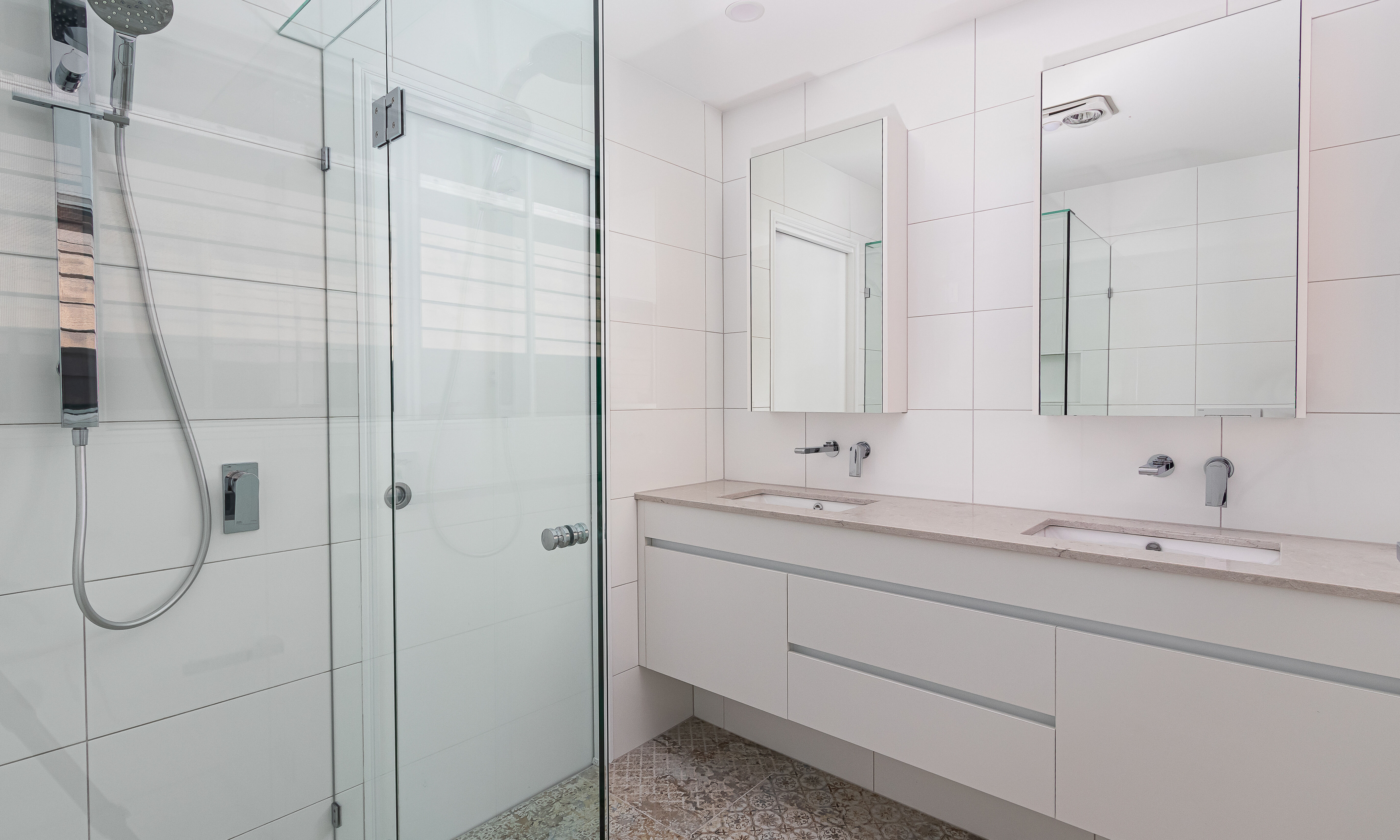 Ensuite with floating vanity, mirrored shaving cabinets and fixed glass shower screen