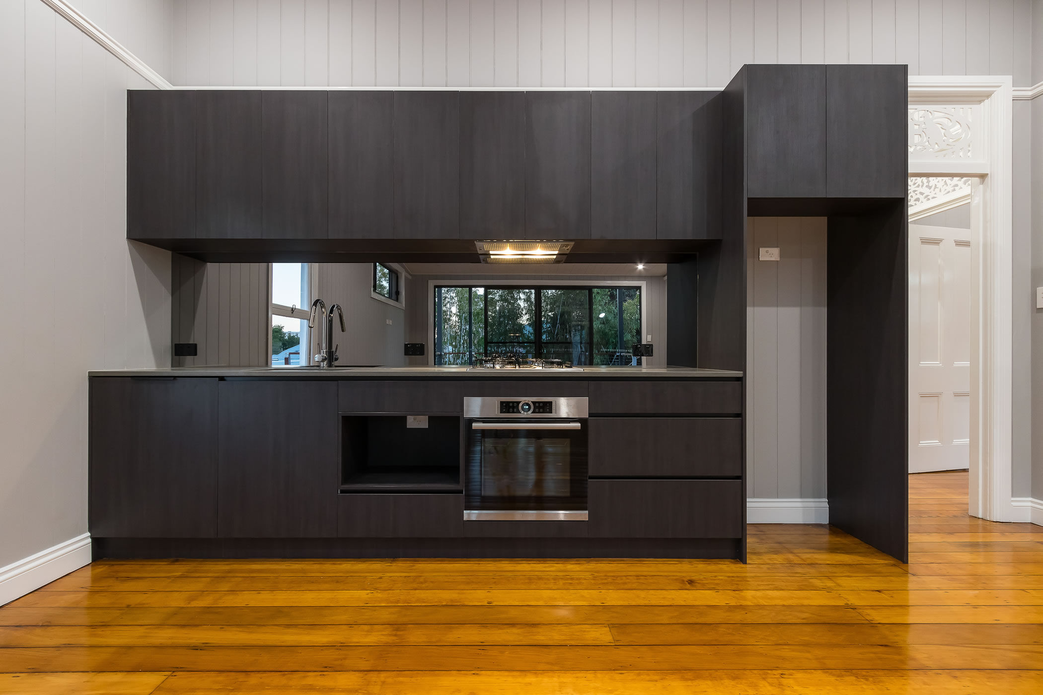 Black kitchen with glass mirrored splashback