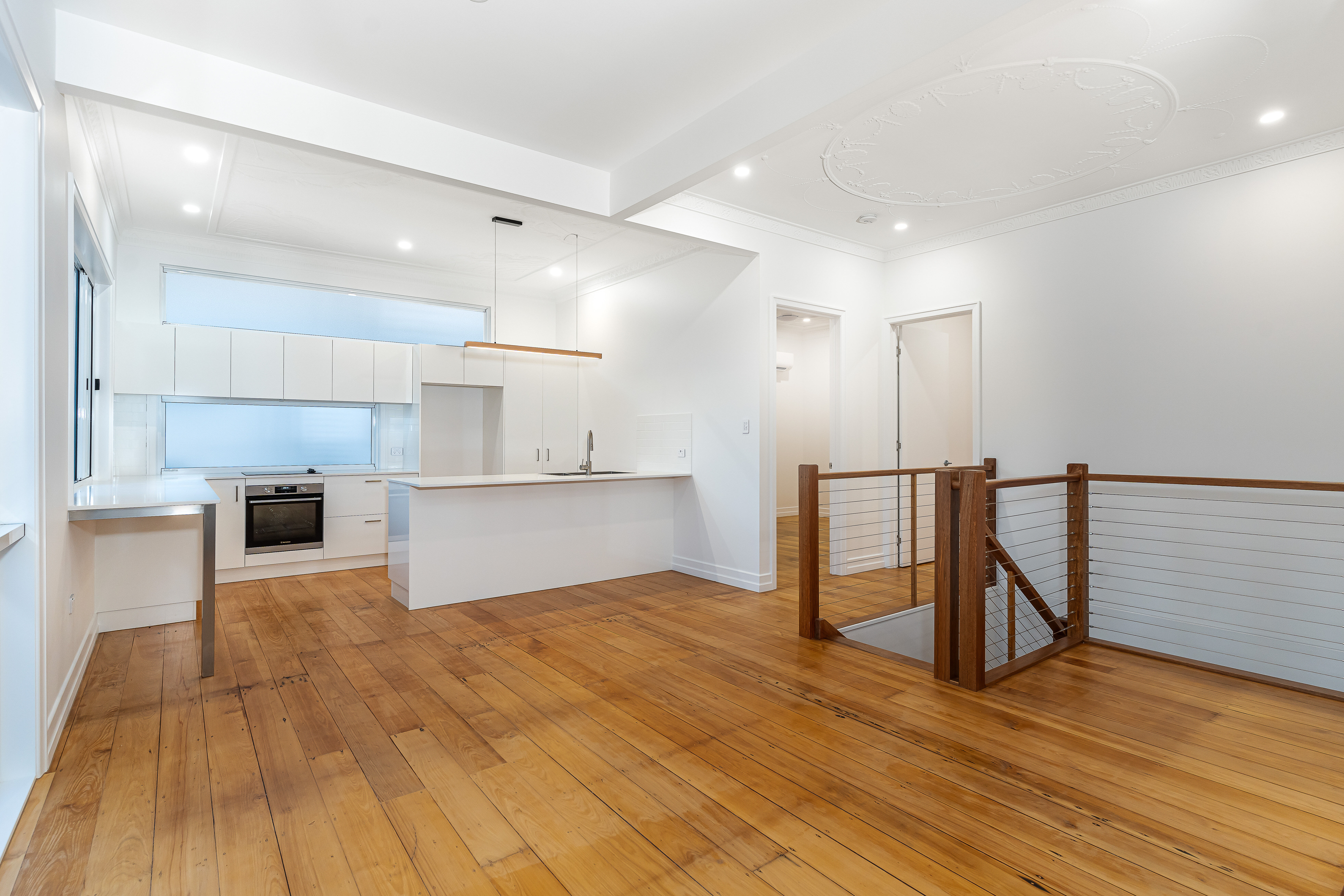 white kitchen- stone bench top-timber stairs-wire balustrade