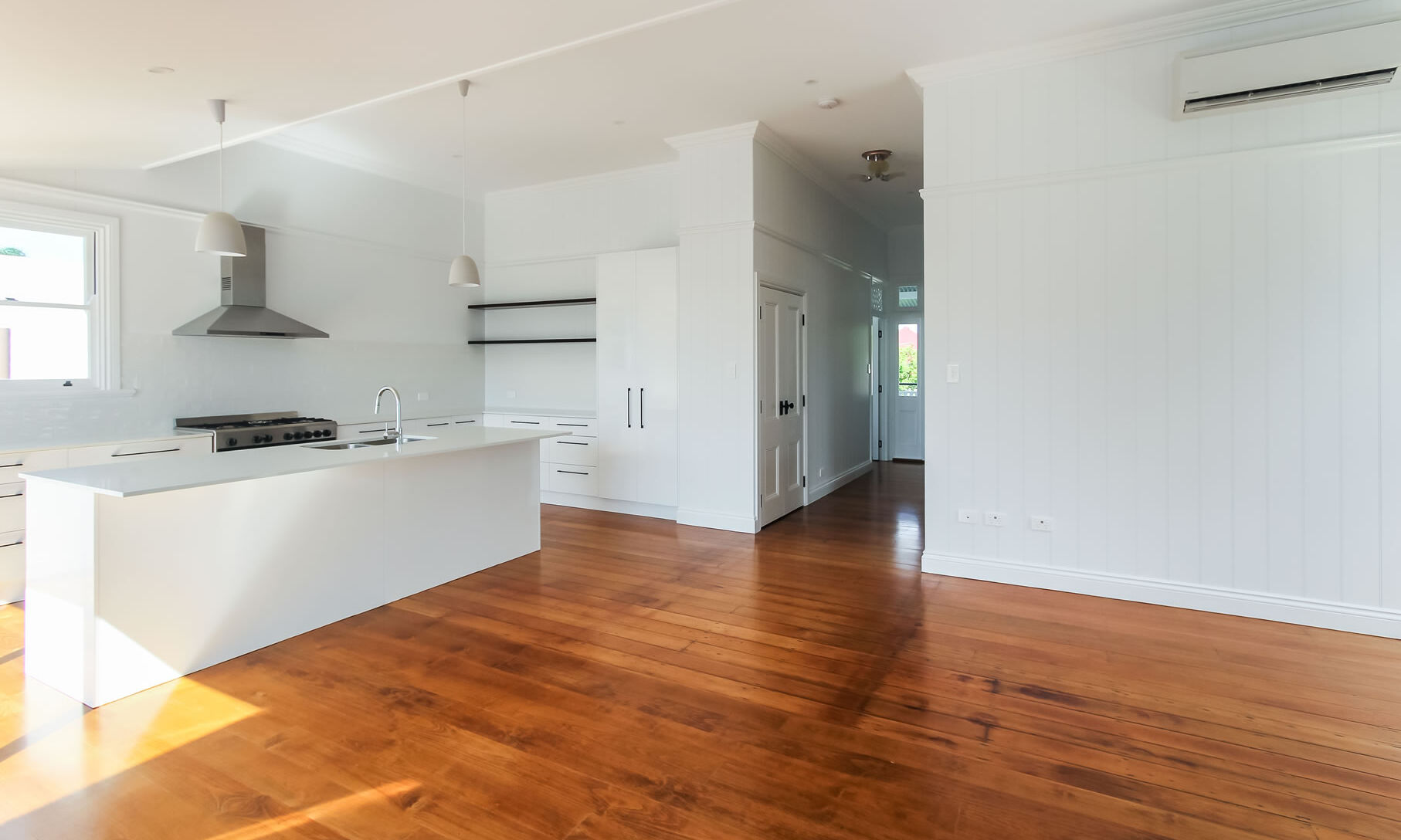 Large white kitchen with island and black handles and knobs